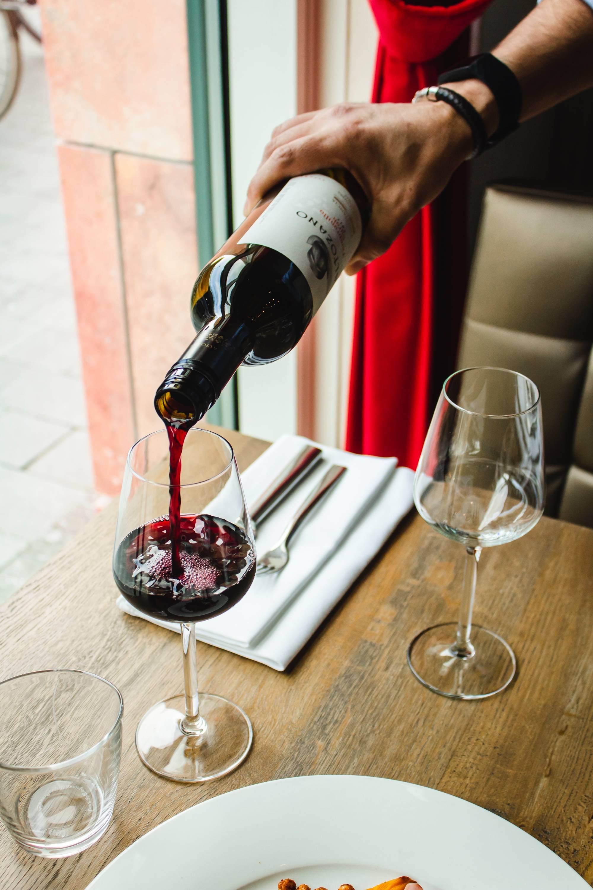 Red wine being poured into a wine glass at a restaurant